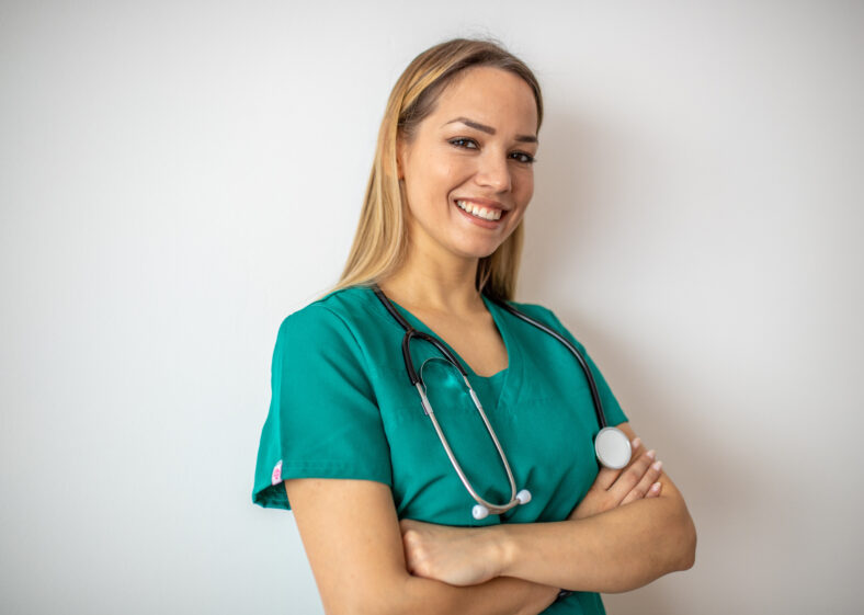 Female nurse standing arms crossed. Confident young woman doctor. Female nurse, young pretty woman in green clothes smiling