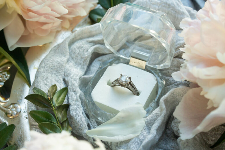 proposal ring in blue box. ribbon and white flower. peony