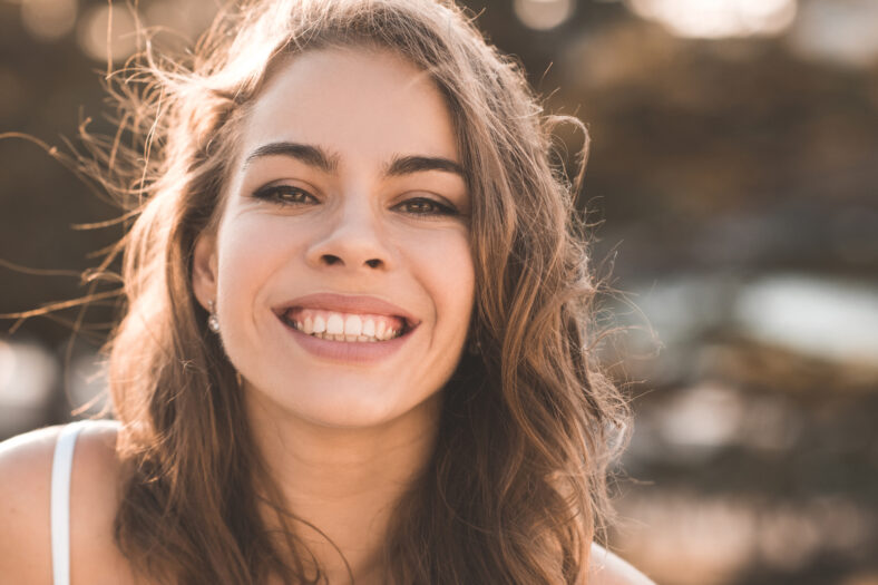 Smiling adult woman 30-35 year old with healthy skin with wrinkles posing outdoors closeup. Summer season. 20s.