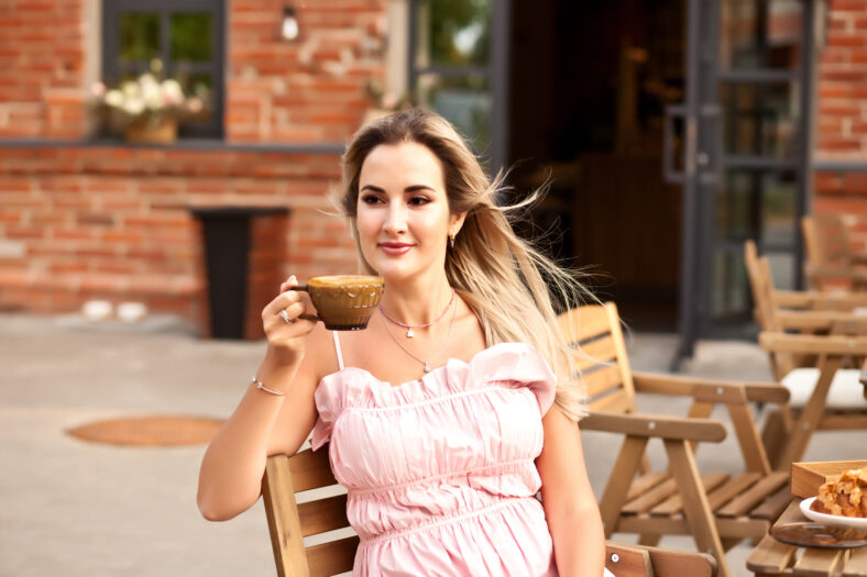 Beautiful woman drinking coffee in a cafe and eating croissant.