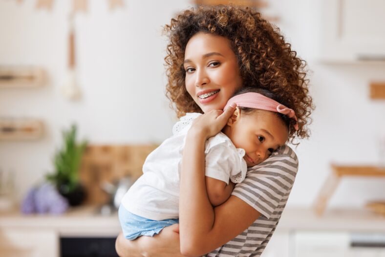 Happy, cheerful african american mother holds a laughing baby daughter in her arms. Concept of motherhood and a loving family