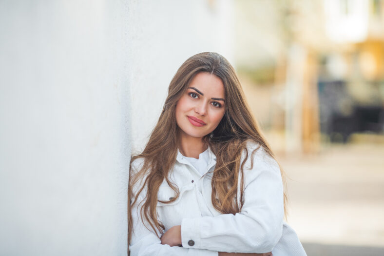 Portrait of a young happy beautiful woman with long hair in light casual comfortable clothes outside. World.