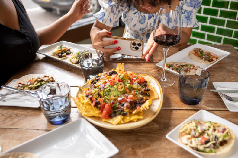 Close-up of woman photographing Mexican food at restaurant table