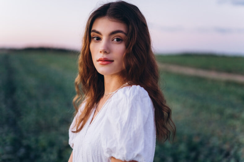 Young girl in white dress in a green meadow. pretty, nice woman