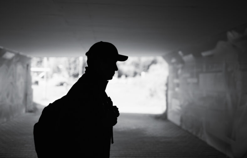 Silhouette of man walking alone in the city caring backpack