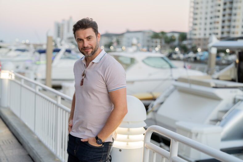 Portrait of handsome male model outdoor. Stylish man dressed in polo. Fashion male posing on the street background. Urban style. Young man walk through the city. Wealthy businessman posing next to office building