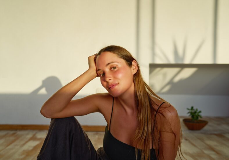 beauty portrait young caucasian woman sitting on the floor posing and smiling carefree indoors