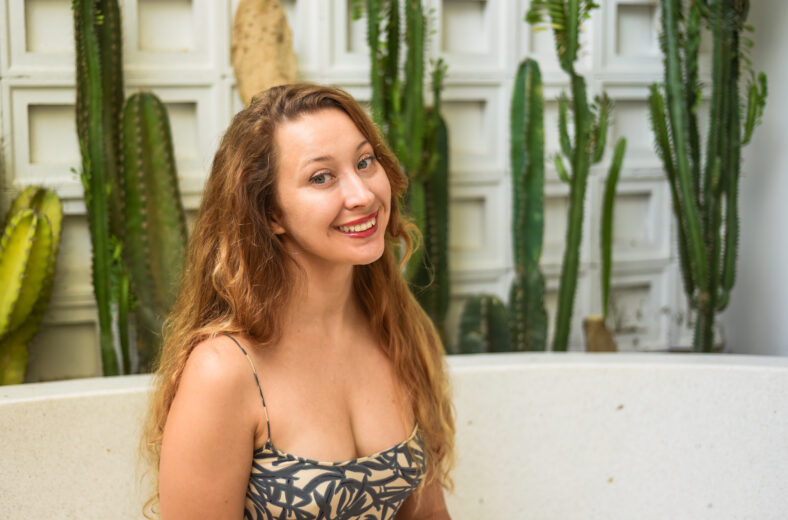 Blonde beautiful woman next to cactuses, portrait close up with copy space
