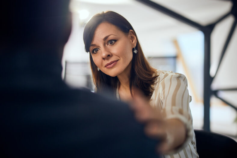 A lovely brunette female therapist listens and talks to a male client during psychotherapy.