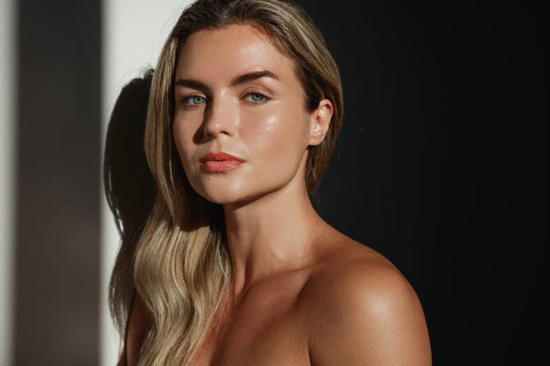 Portrait of young woman with long blonde hair in sunlight.