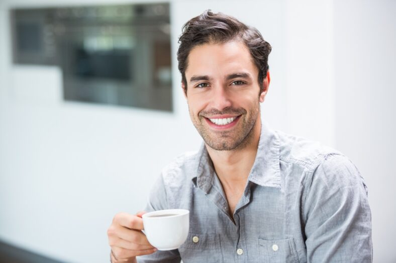 Smiling young man holding coffee cup