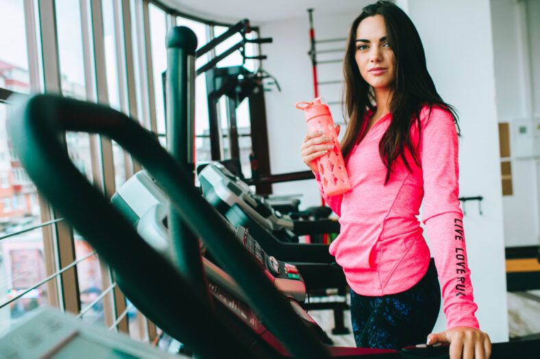 young girl at the gym trainer holding a bottle of water