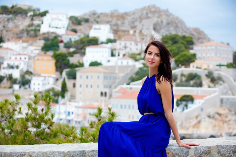 photo of beautiful young woman sitting on the stairs on the town background in Greece