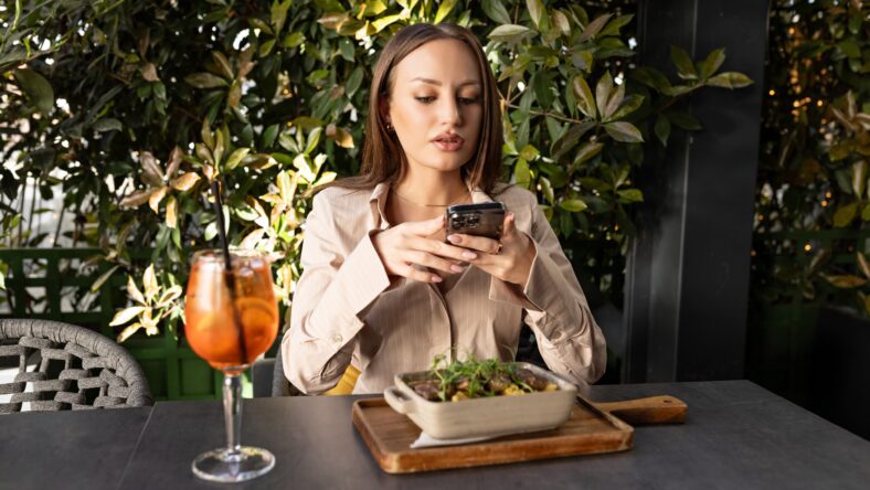 Woman browsing her phone during a meal at a café