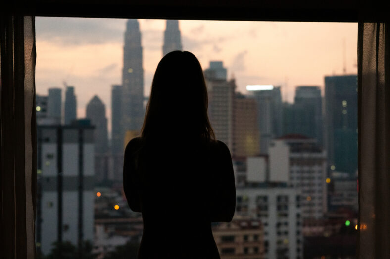 Silhouette of woman at sunset with city skyline