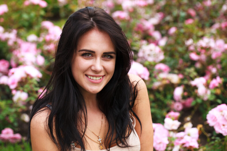Portrait of a beautiful young woman on a background of spring flowers park