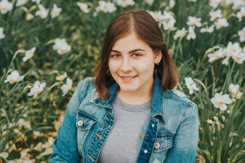 Outdoor portrait of young teenage 16 year old girl, wearing denim jacket