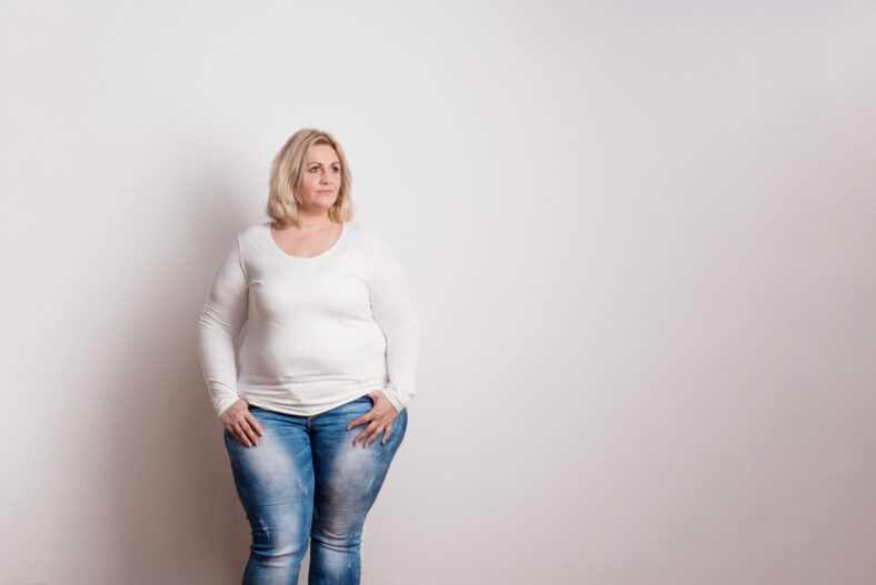 Portrait of an attractive blond overweight woman in studio on a white background. Copy space.