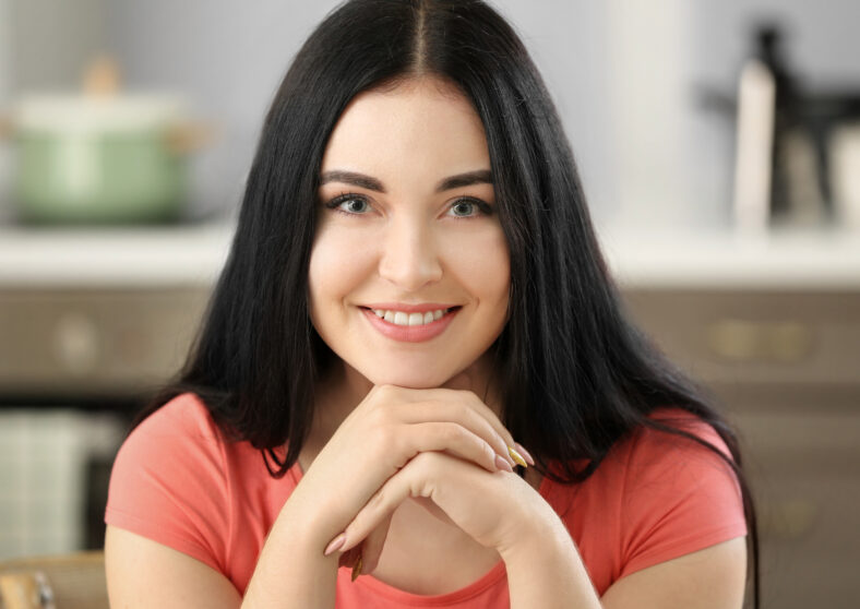 Portrait of young beautiful woman smiling in kitchen