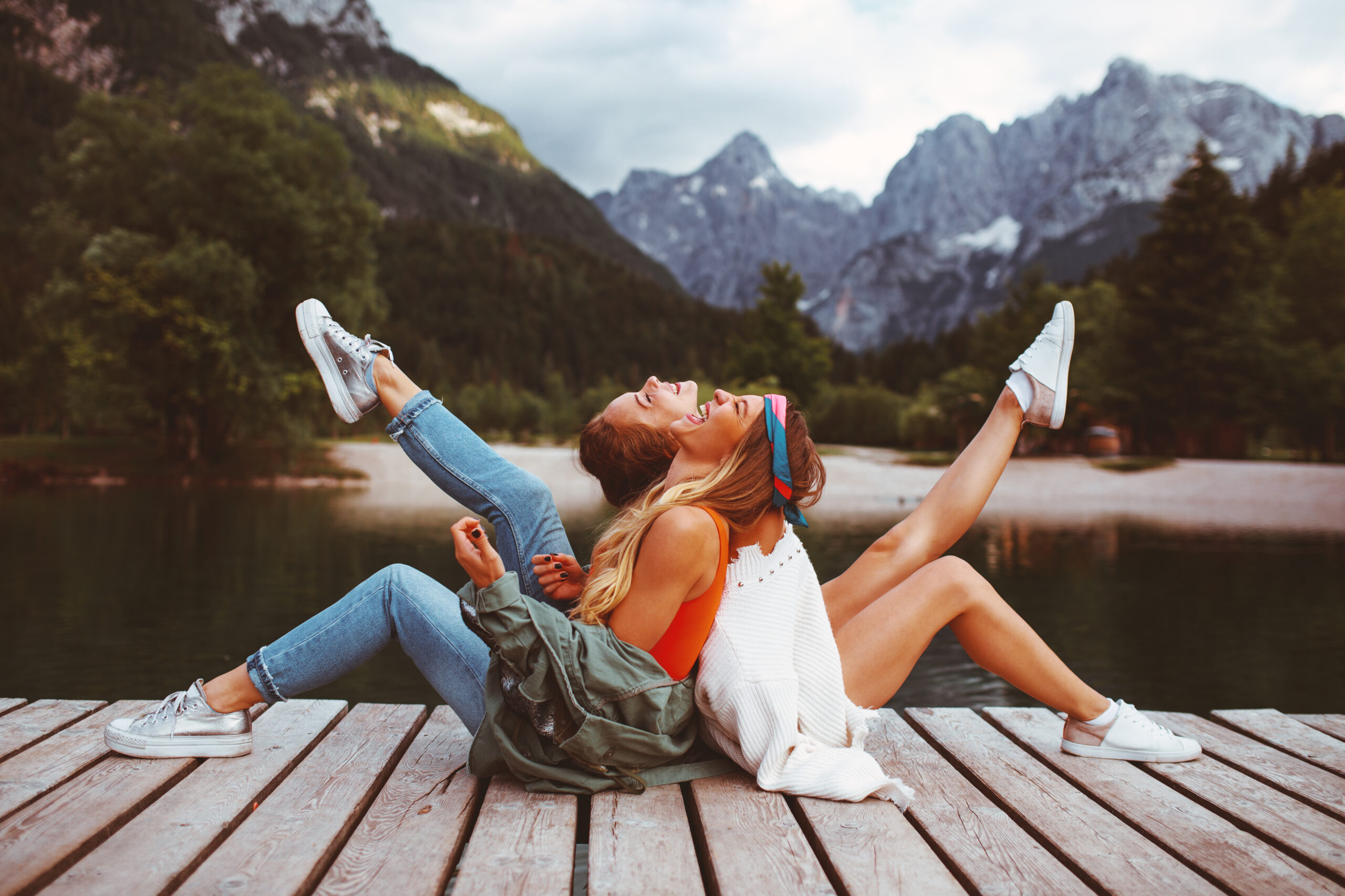 Two young tourist women have fun on the dock on lake