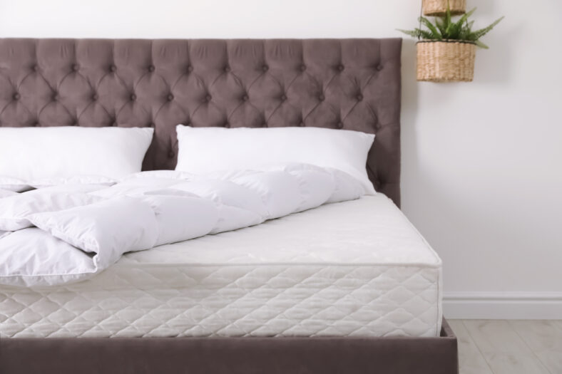 Cama cómoda con colchón nuevo en la habitación. Sueño saludable
