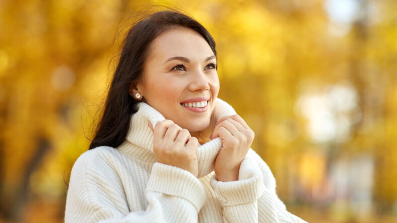 season and people concept - portrait of happy young woman smiling in autumn park