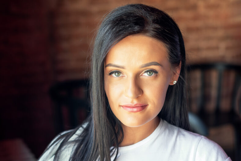 Portrait of beautiful woman is sitting at cafe. Happy woman relaxing and smiling at cafe.
