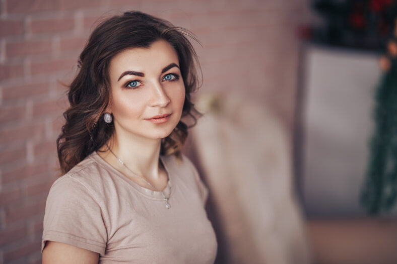 Young woman sitting in luxury beautiful begie armchair on flowers background
