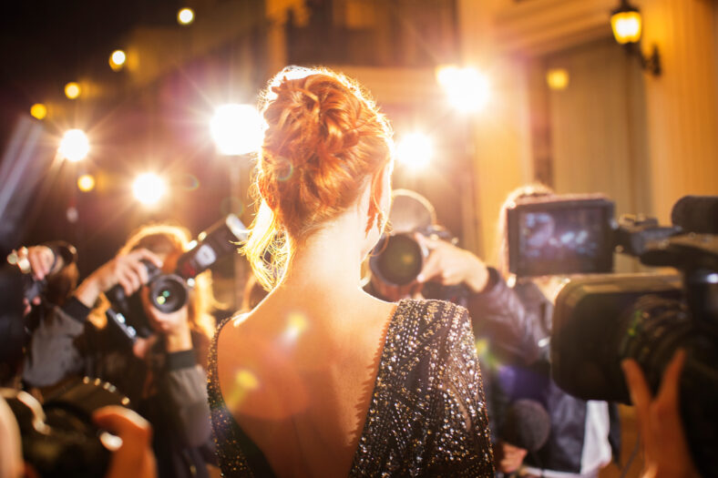 Celebrity being photographed by paparazzi photographers at event