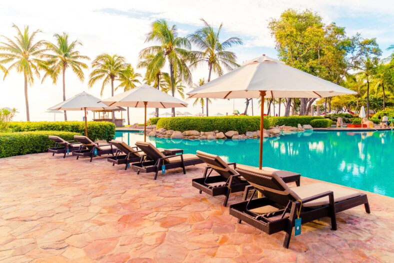 Umbrella and chair around swimming pool in resort hotel for leisure travel and vacation neary sea ocean beach at sunset or sunrise time