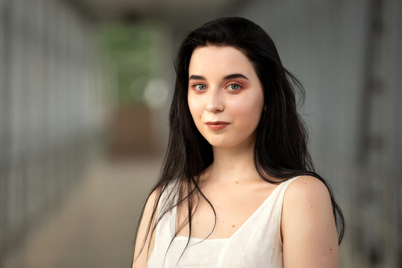 Portrait of a beautiful brunette in a light dress on the street in a pedestrian crossing on a summer day