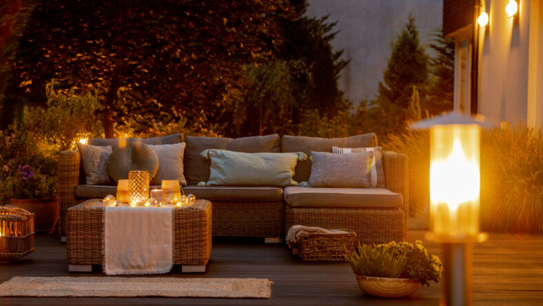 Warm summer night in the garden with trendy furniture, lights, lanterns and candles