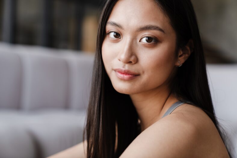 Image of pleased beautiful asian girl posing and looking at camera at home