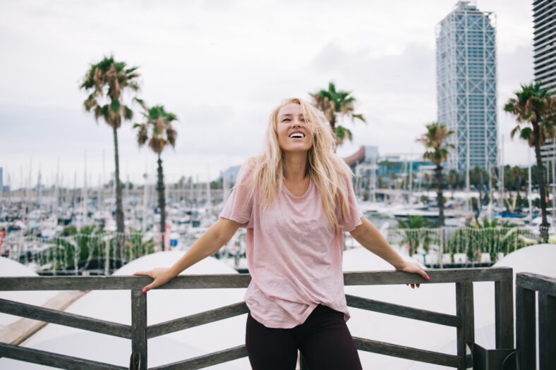 Gorgeous emotional woman with perfect sincerely smile on face rejoicing at city urban setting, joyful Caucasian female tourist dressed in stylish casual wear laughing during leisure at city