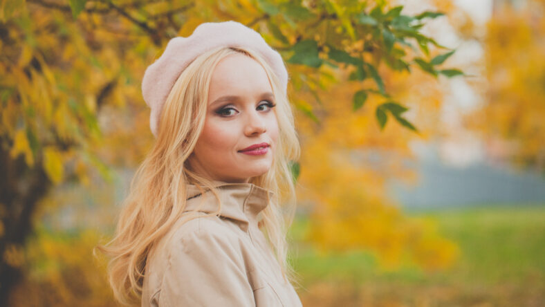 Autumn mood. Happy young woman on yellow nature background