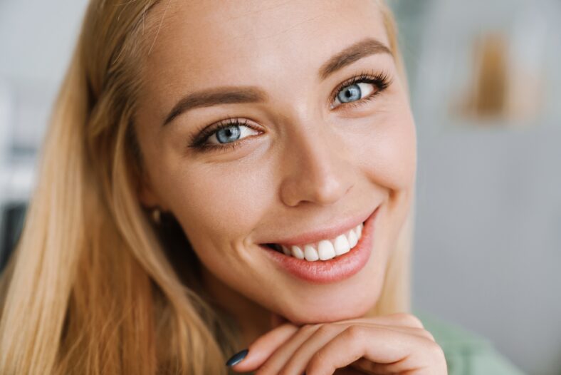 Happy blonde young woman smiling and looking at camera indoors