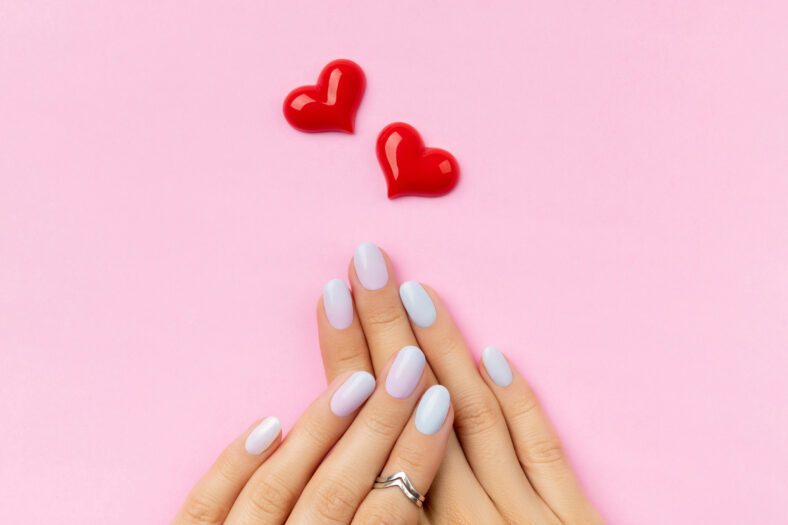 Womans hands with trendy manicure on pink background. Summer nail design. Beauty salon concept