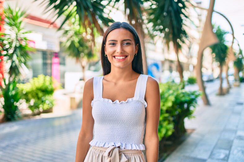 Young latin girl smiling happy walking at street of city.
