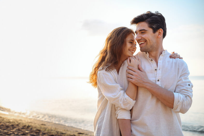Smiling young couple two friends family man woman 20s in casual clothes hug girlfriend put head on boyfriend shoulder at sunrise over sea sand beach ocean outdoor seaside in summer day sunset evening