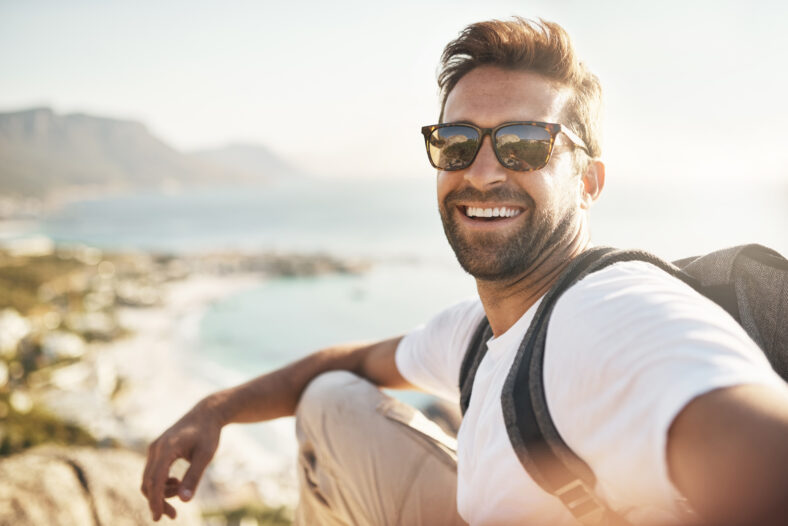 Retrato recortado de un joven guapo tomando selfies mientras camina en las montañas.