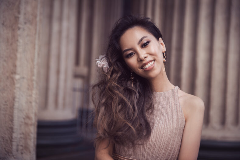 Close-up portrait of young asian beautiful woman in dress near columns outdoors
