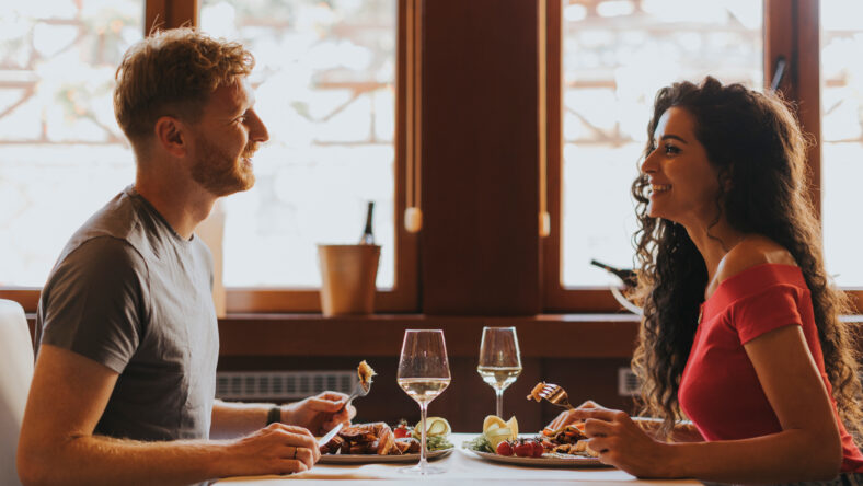 Handsome young couple having lunch with white wine in the restaurant