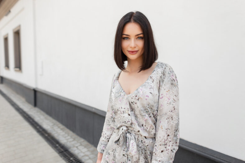 Urban female summer portrait of beautiful woman with hairstyle in fashion spring flowers dress walks in the city