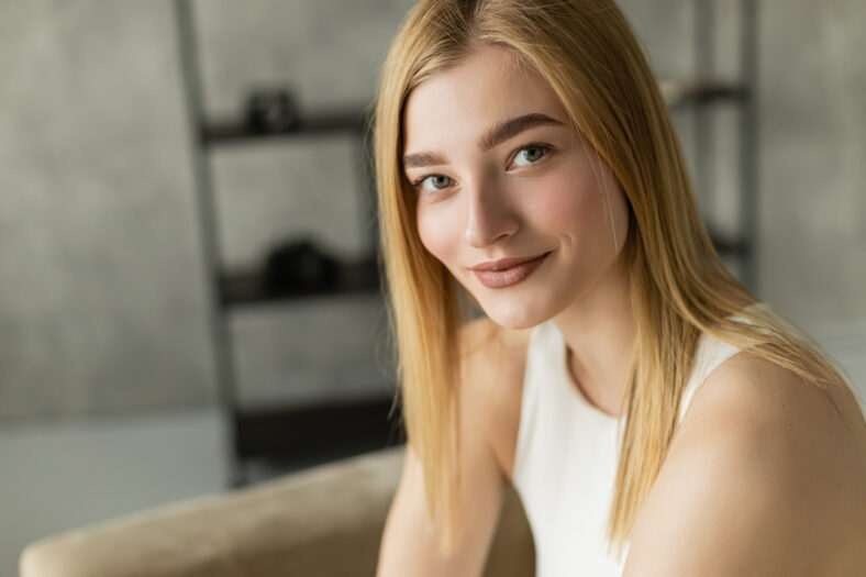 Portrait of blonde young woman smiling at camera at home,stock image
