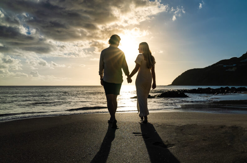 silhouette of young engaged couple holding hands in love during the sunset on a sandy island beach