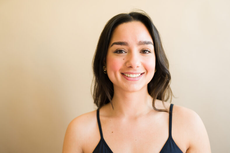 Gorgeous brunette caucasian woman smiling looking beautiful and happy against a feminine studio background