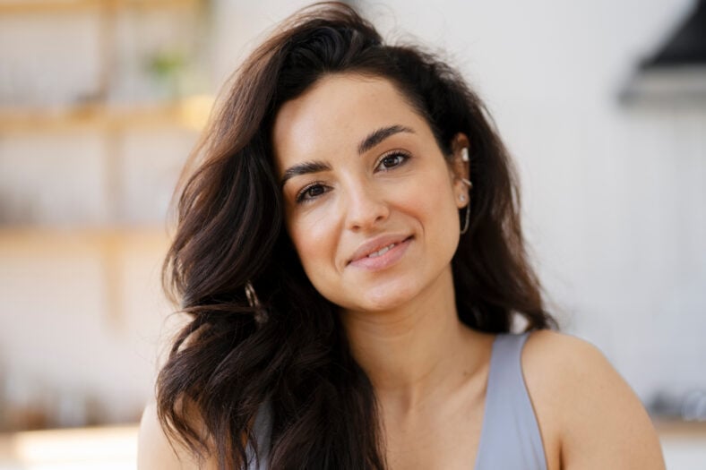 Closeup portrait of beautiful smiling latin woman looking at camera standing in kitchen. Positive emotions, healthy lifestyle concept