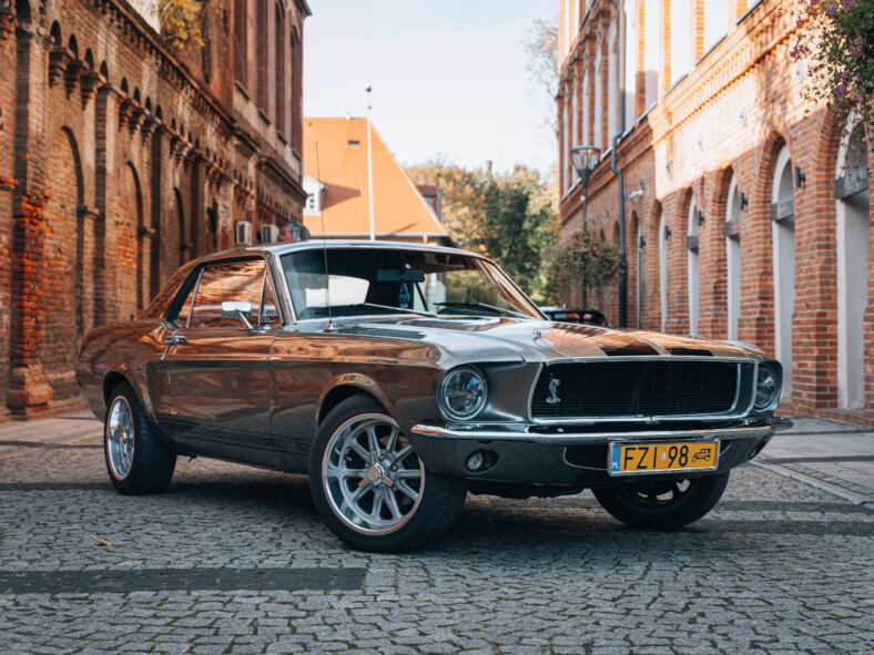 Vintage Ford Mustang GT 1967 estacionó en el medio de Industrial Road en un día soleado. Diseño americano con llantas de aleación. Perfecto para artículos de marketing, publicidad o prensa.