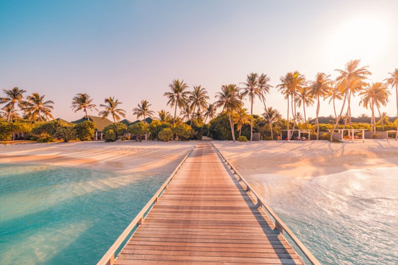 Amazing sunset panorama at Maldives. Luxury resort villas seascape with soft led lights under colorful sky. Beautiful twilight sky and colorful clouds. Beautiful beach background for vacation holiday