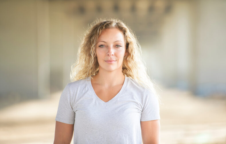 A portrait caucasian woman with fresh and clean skin stands outside on industrial background
